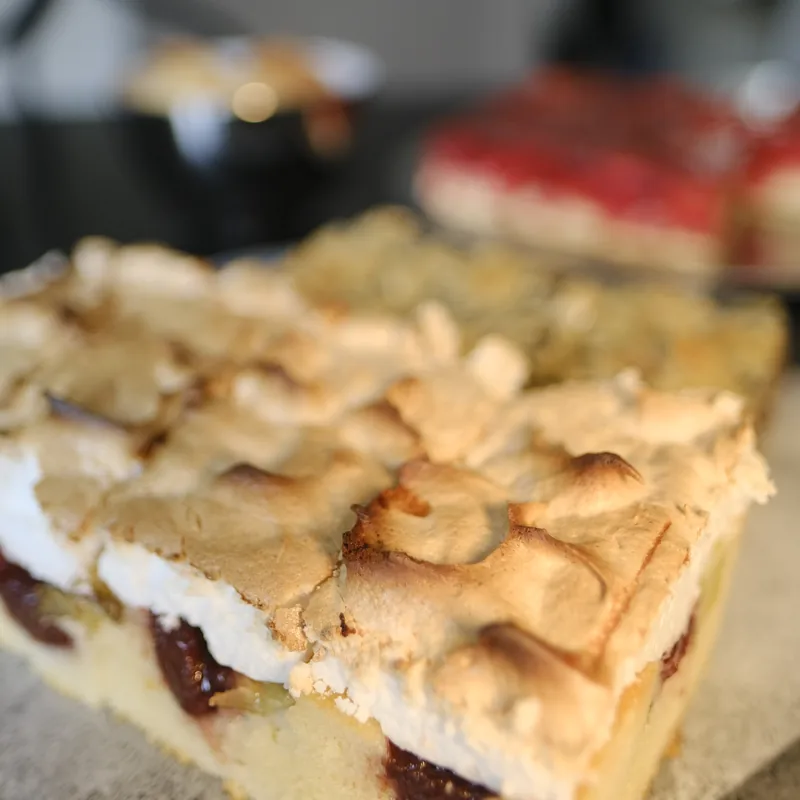 Blechkuchen mit Kirschen unter einer Baiserhaube.