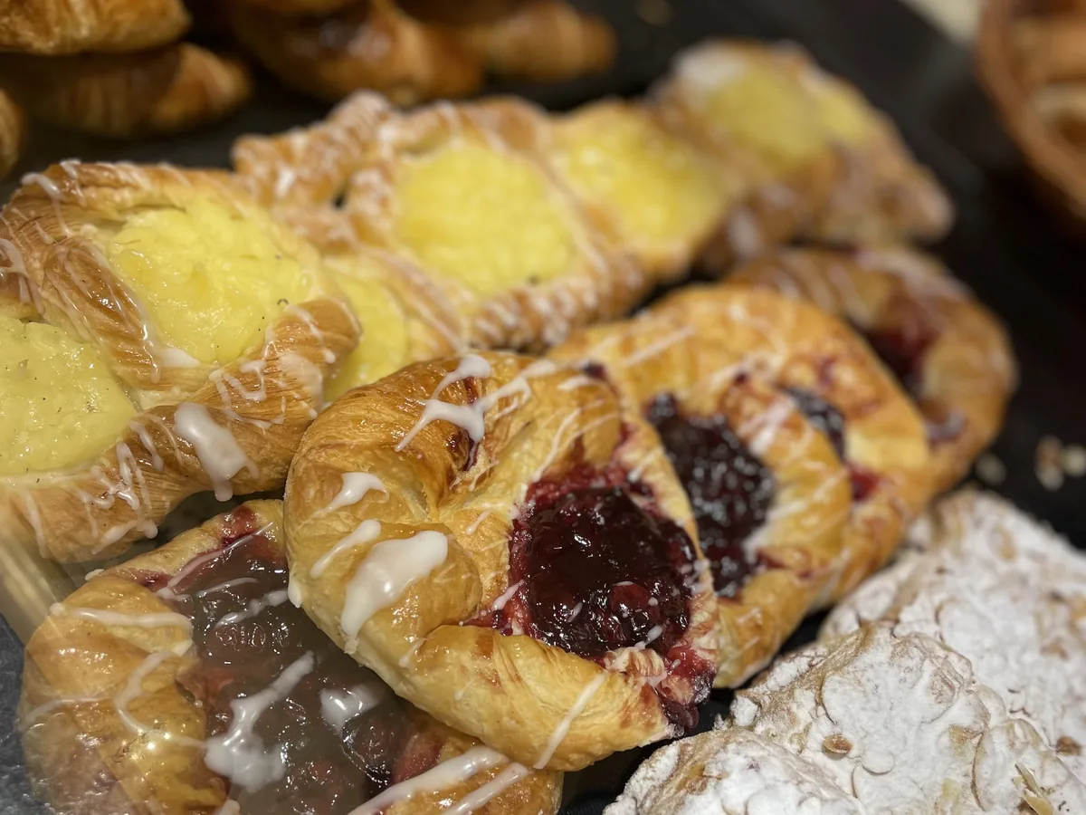 Plunderteilchen mit Puddingfüllung und Kirschplunder, mit Zuckerguss überzogen, dicht an dicht in der Auslage.
