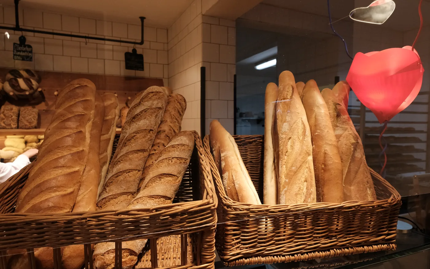 Baguettes und Brote stehen aufrecht in Weidenkörben im Verkaufsregal.