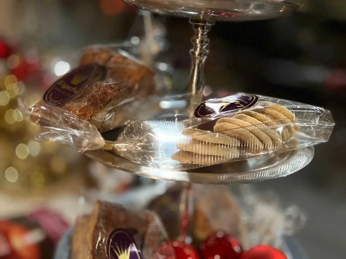 Eine Etagere mit verpacktem Weihnachtsgebäck, davor rote Christbaumkugeln.