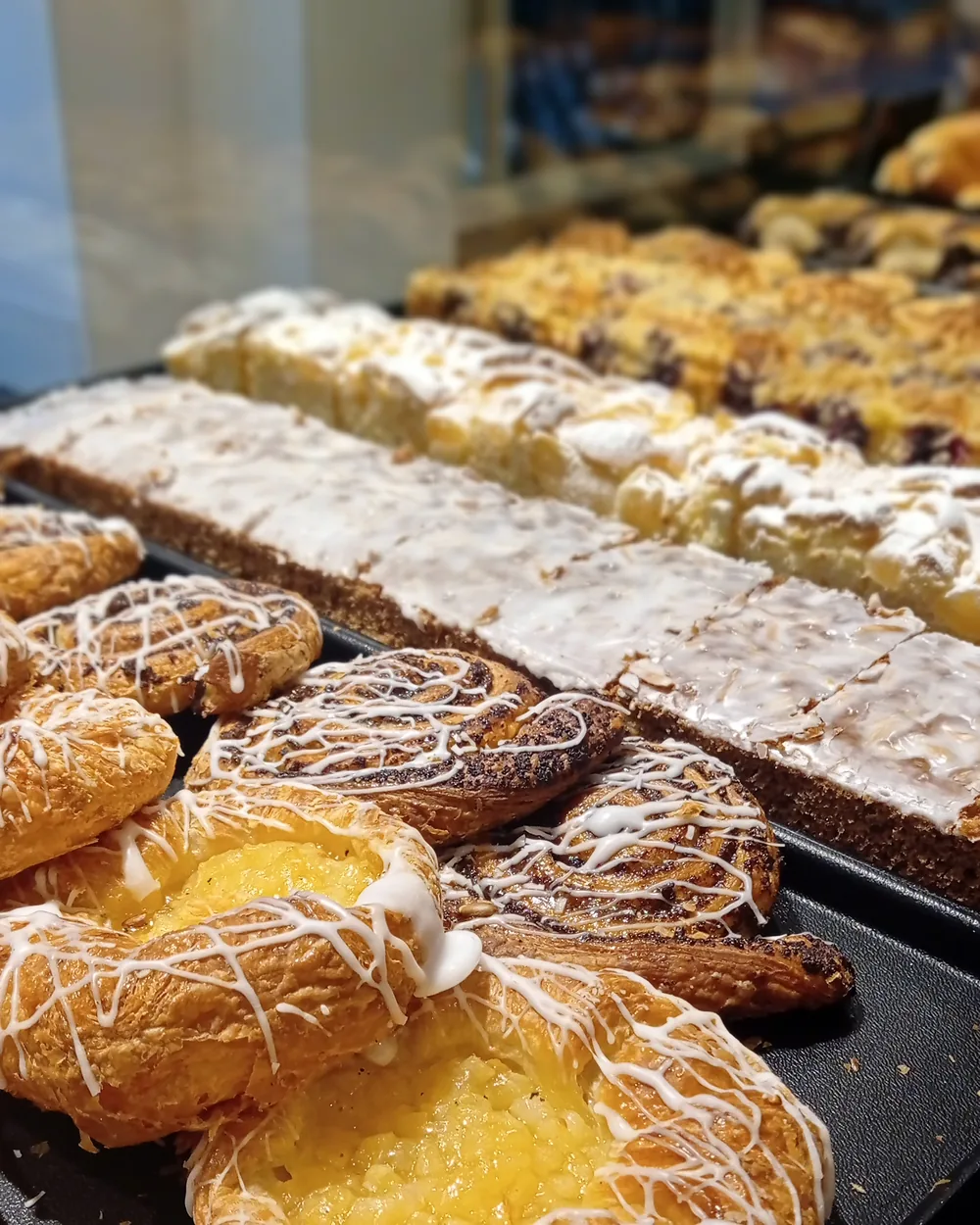 Plundergebäck in der Auslage: Vanilleschnecken, Teilchen mit Zuckerguss und Streuselschnitten.