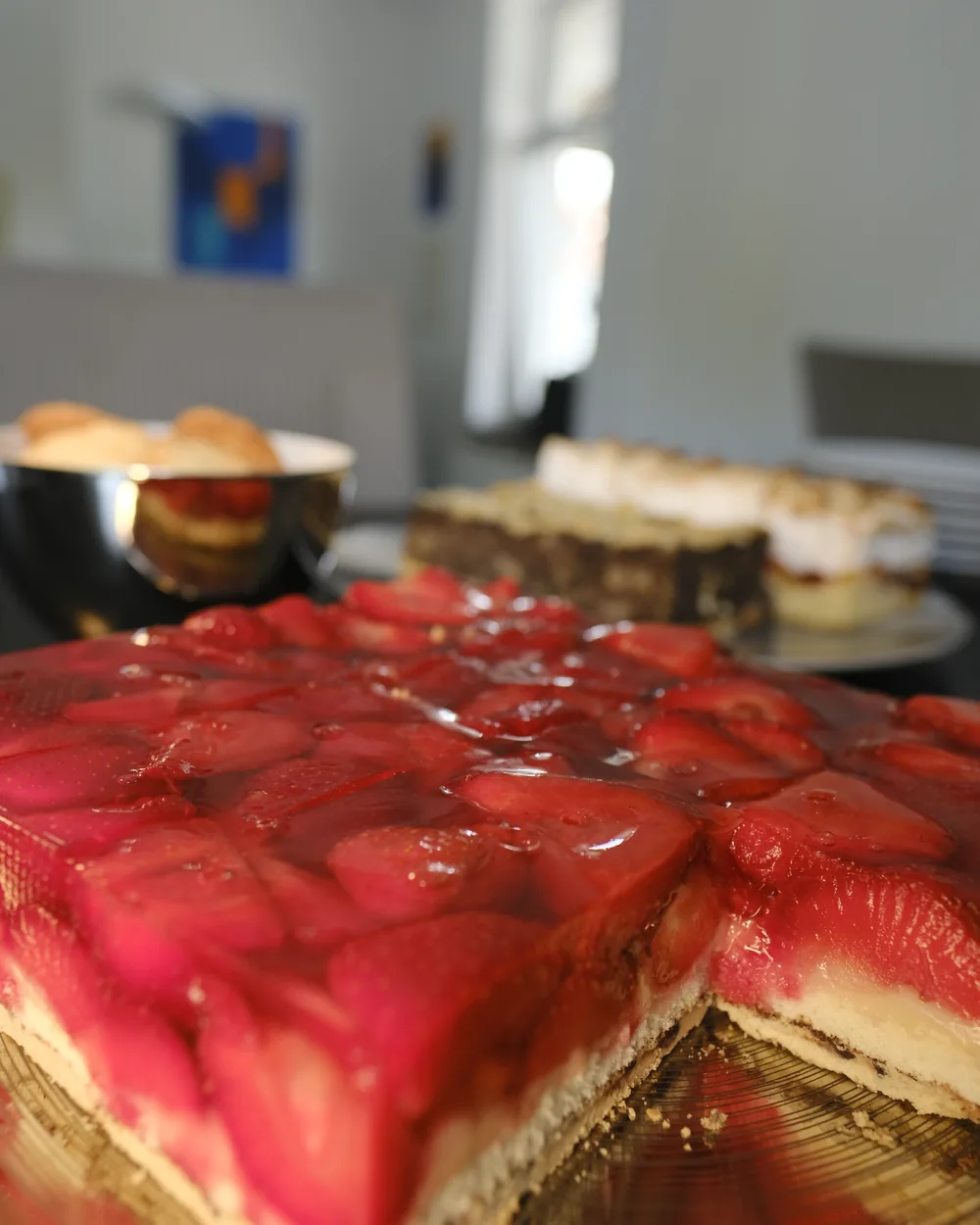 Erdbeer-Blechkuchen im Anschnitt, die Erdbeeren unter glänzendem Guss.